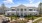 a white building with a lawn and trees in front of it