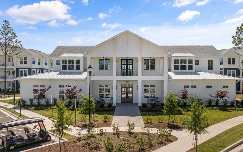 a white building with a lawn and trees in front of it